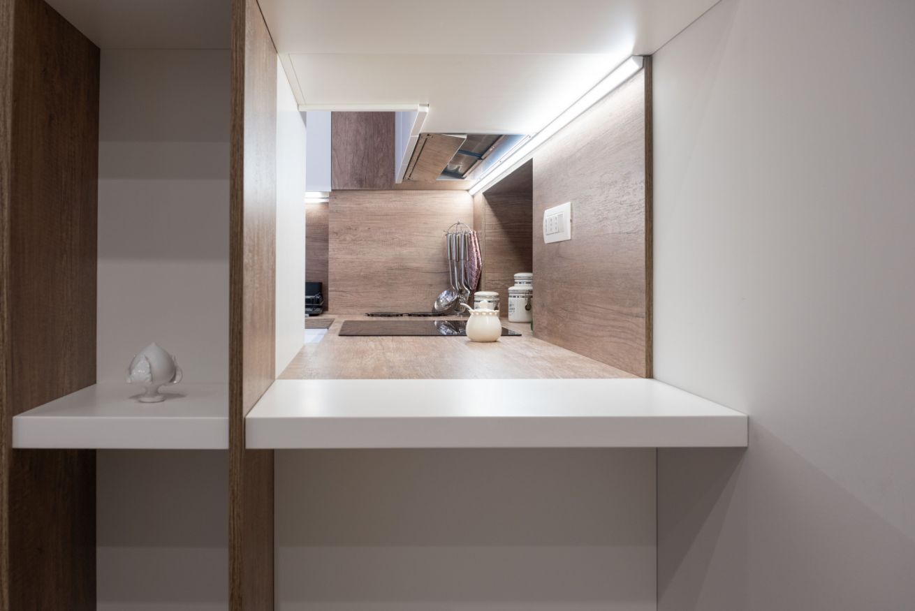 A modern kitchen with a wooden countertop, a hanging rack, and a small island.