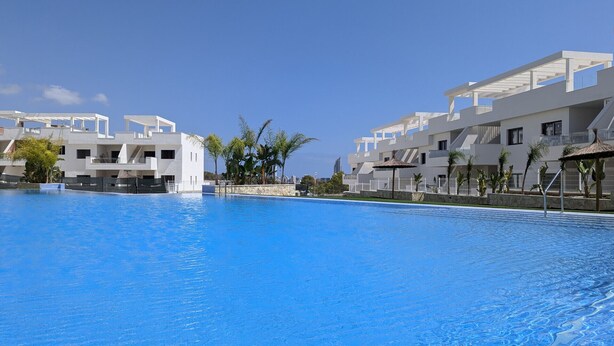 Una piscina con edificios blancos modernos al fondo.