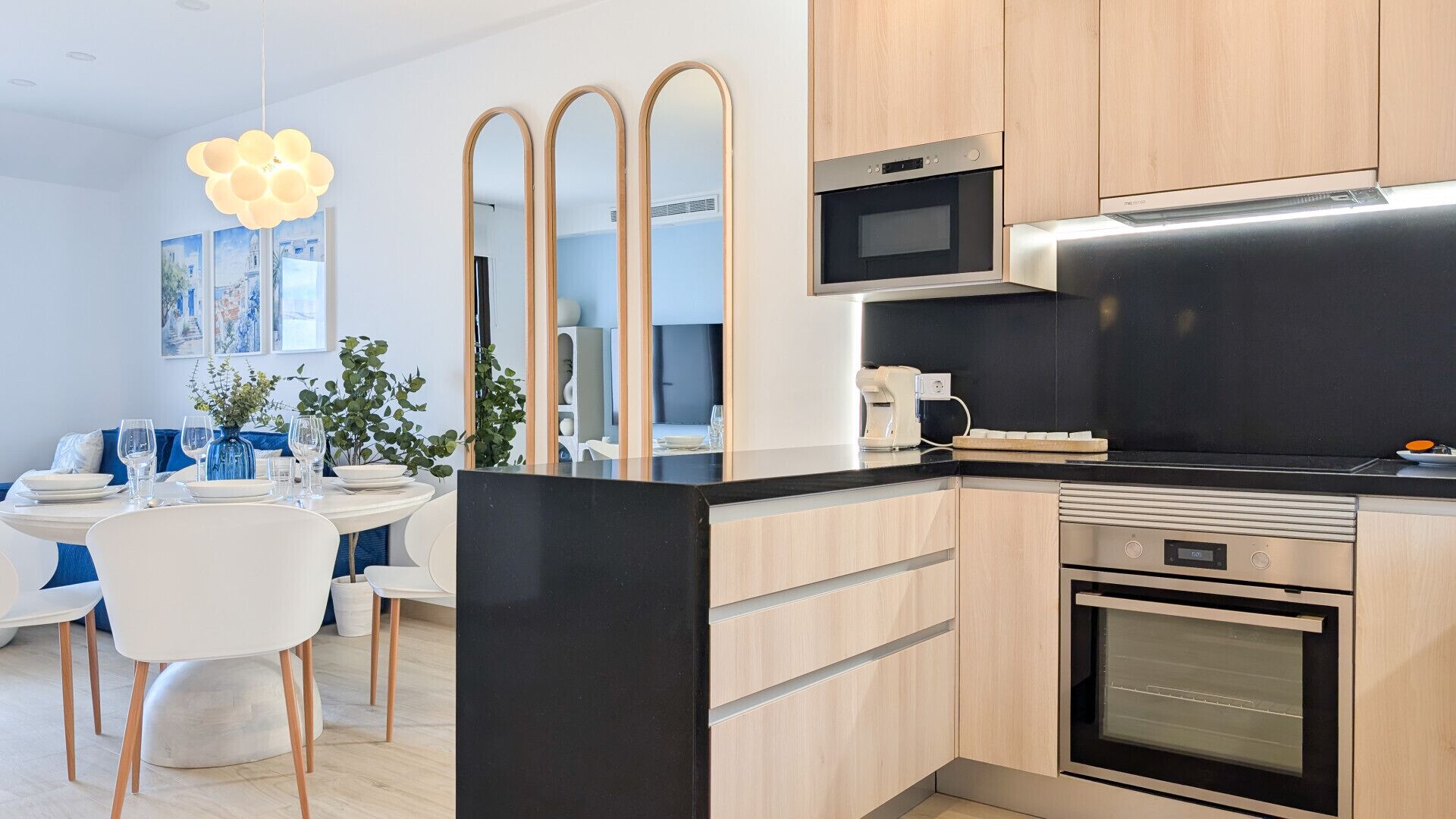 Une cuisine moderne avec un plan de travail noir, des appareils en acier inoxydable et des meubles en bois.