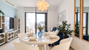 Un comedor moderno con una mesa redonda para cuatro, un televisor y un amplio ventanal con vistas al exterior.
