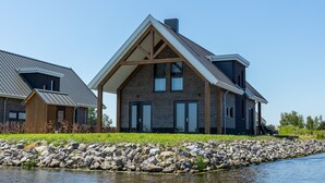 Una casa moderna con un llamativo techo triangular, ventanas amplias y una base de piedra.