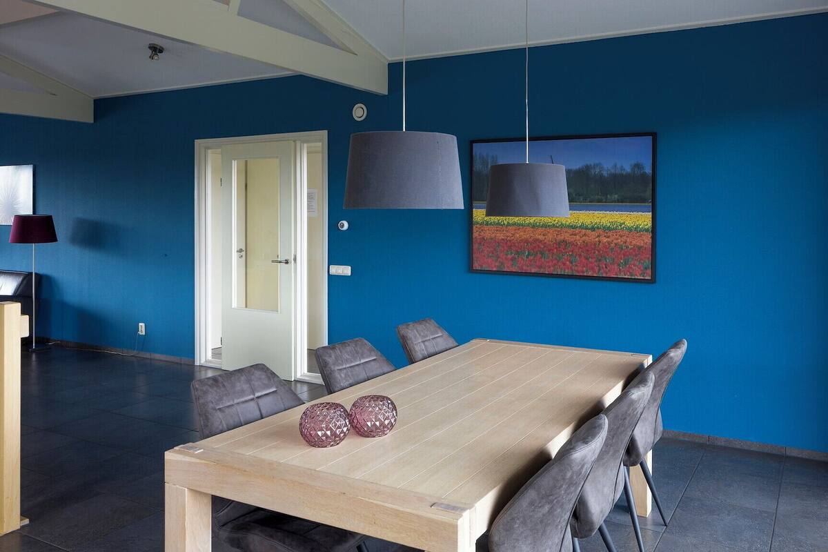 A dining area with a wooden table, grey upholstered chairs, and pendant lights.