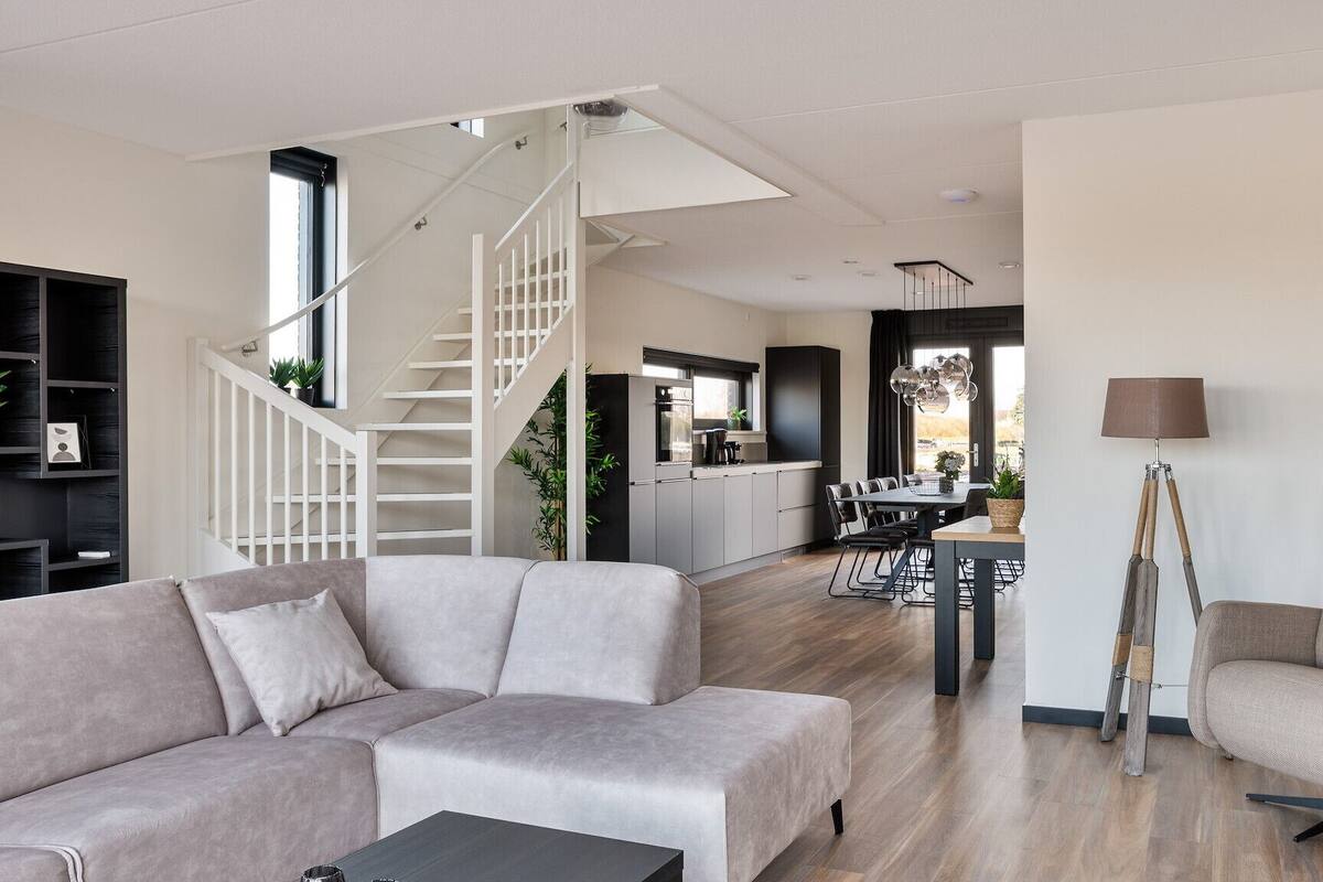 A modern living room with a staircase, a dining area, and a kitchen.