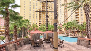 A poolside area with wooden decking, lounge chairs, and umbrellas. - 2BR-Dlx Inside Disney Gates-5 Pools, 2 Lazy Rivers, SPLASH pad, Mini Golf & More (Lake Buena Vista)