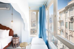 Une chambre à coucher avec un lit, une table de chevet et une fenêtre donnant sur la ville.
