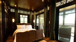 A traditional wooden bed with white linens, a patterned rug, and a large window with curtains. - Akara House Sukhothai (Si Satchanalai)