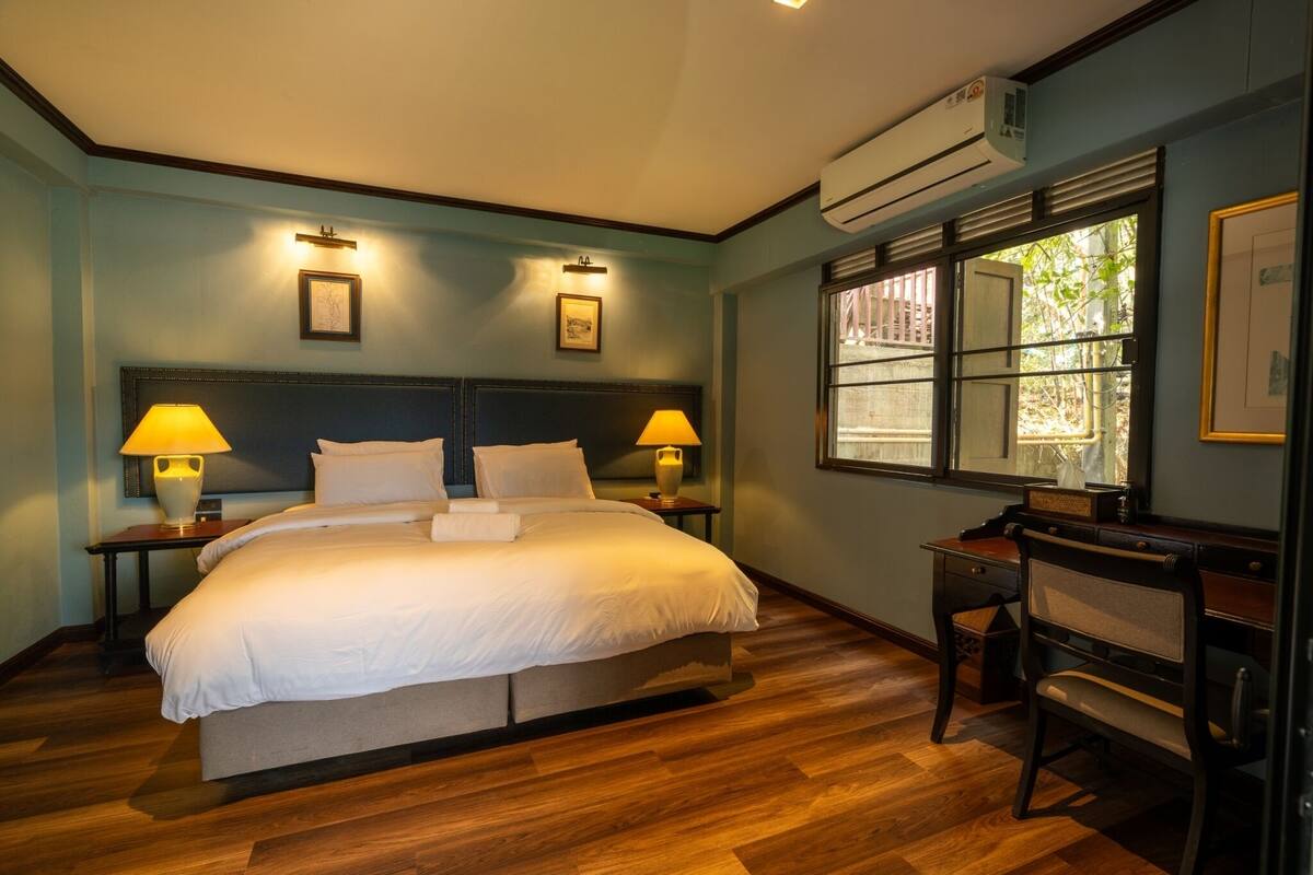 A hotel room with a large bed, two bedside lamps, a desk, and a chair.