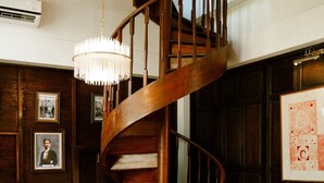 A traditional room with a wooden spiral staircase, leather armchair, and a sofa. - Akara House Sukhothai (Si Satchanalai)