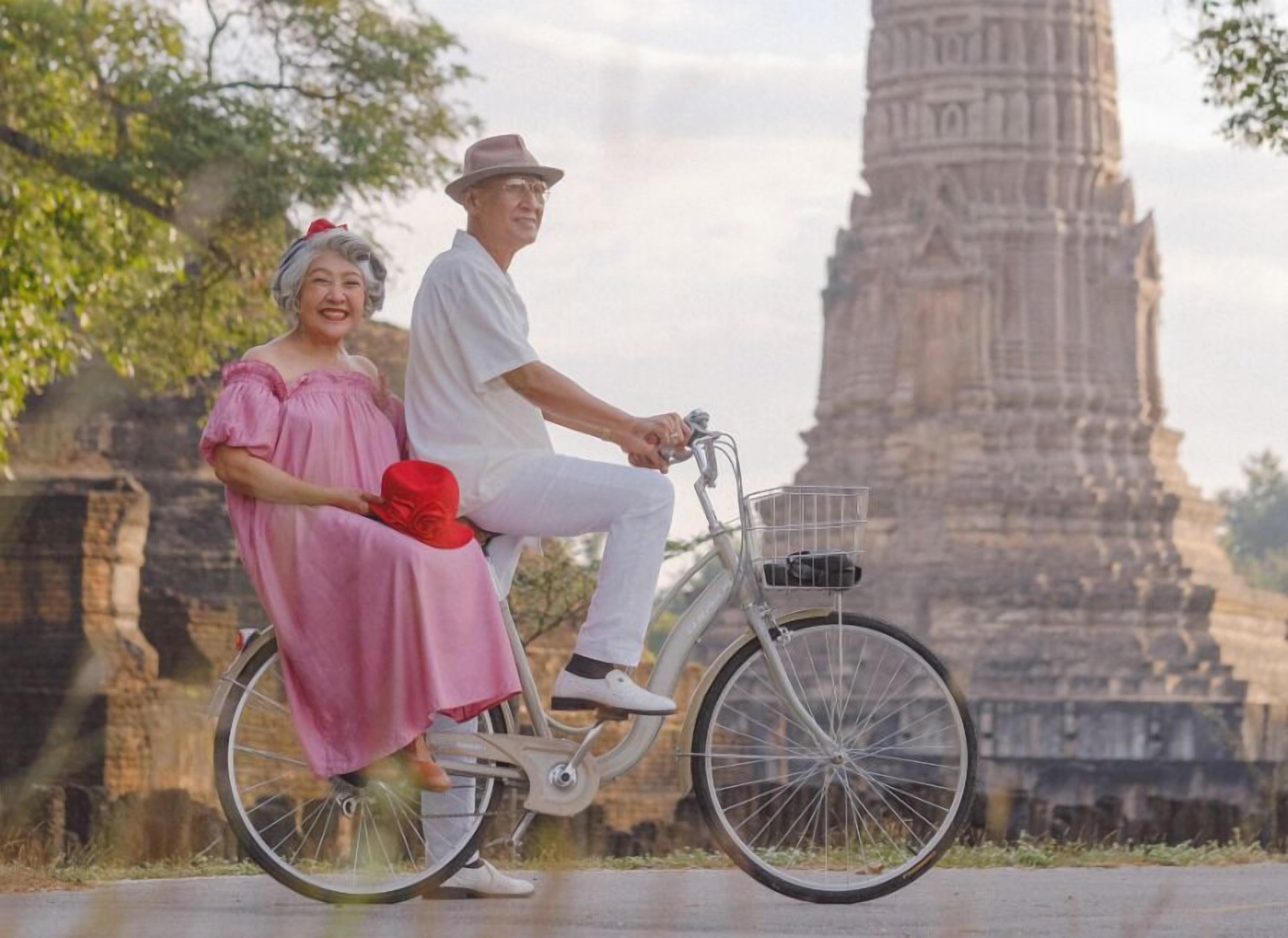 A couple on a bicycle with a historic temple in the background.