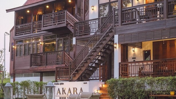 A multi-story building with a traditional architectural style, featuring balconies and a staircase. - Akara House Sukhothai (Si Satchanalai)