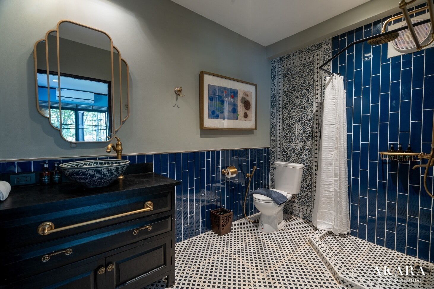 A bathroom with a black vanity, a sink with a decorative bowl, a toilet, and a shower area with blue tiles.