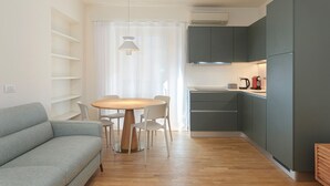 A modern kitchen with grey cabinets, a round wooden table, and a grey sofa. - easyhomes - Repubblica (Milan)