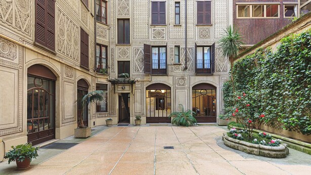 A courtyard with a tiled floor, a central entrance, and a building with ornate architectural details. - easyhomes - Repubblica (Milan)