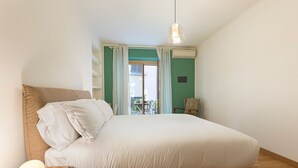 A bedroom with a bed, a bedside table, a chair, and a view of the outside. - easyhomes - Repubblica (Milan)