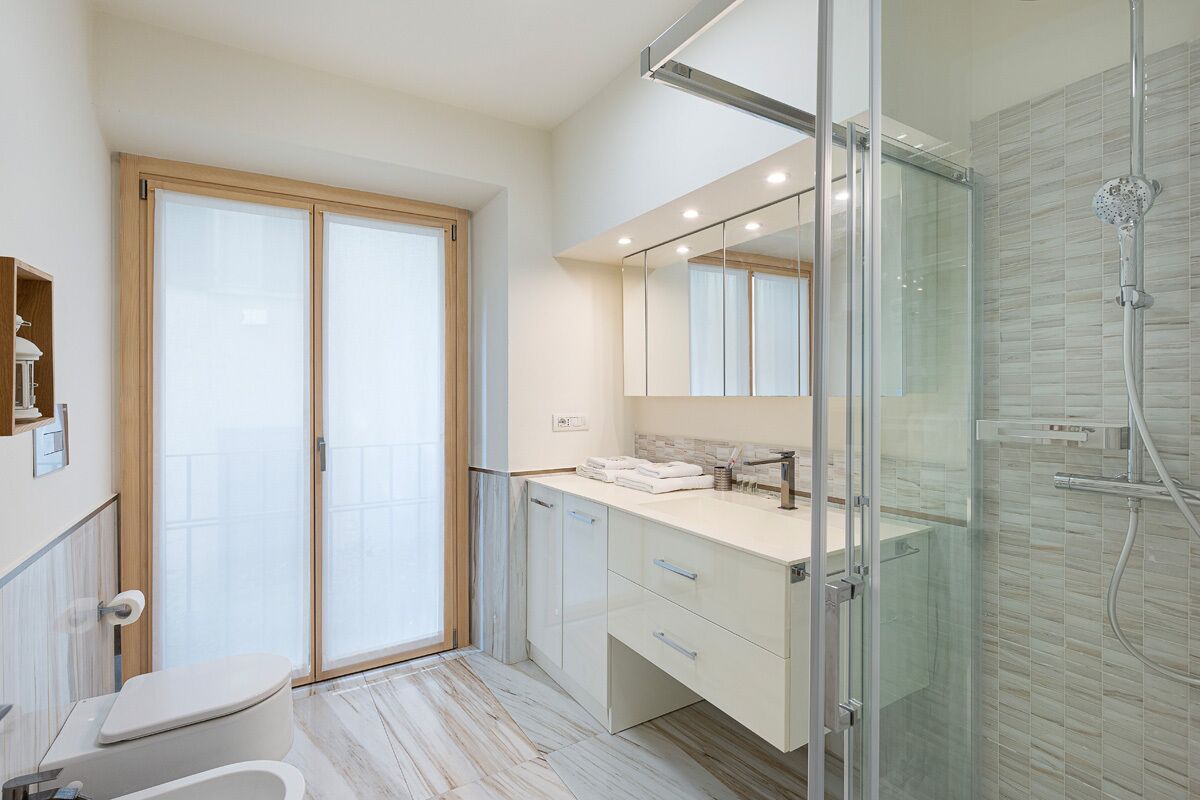 A modern bathroom with a glass shower enclosure, a toilet, and a vanity with a mirror.