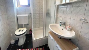Une salle de bain équipée de toilettes, d’une douche, d’un lavabo et d’une fenêtre.