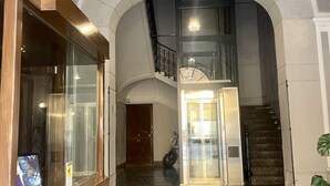 A spacious interior with a grand staircase, a glass door entrance, and a view of the upper floor. - The House of Paintings Spacious cozy art house in the heart of the Palermo city (Palermo)