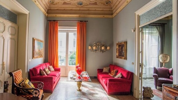 A room with two red sofas, a glass coffee table, and a chandelier. - The House of Paintings Spacious cozy art house in the heart of the Palermo city (Palermo)