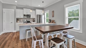 A kitchen with white cabinets, a wooden island, and pendant lighting. - The Beacon, Steps From The Beach (Carolina Beach)