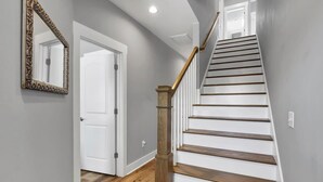 A staircase with wooden steps and a wooden handrail, leading to a white door. - The Beacon, Steps From The Beach (Carolina Beach)