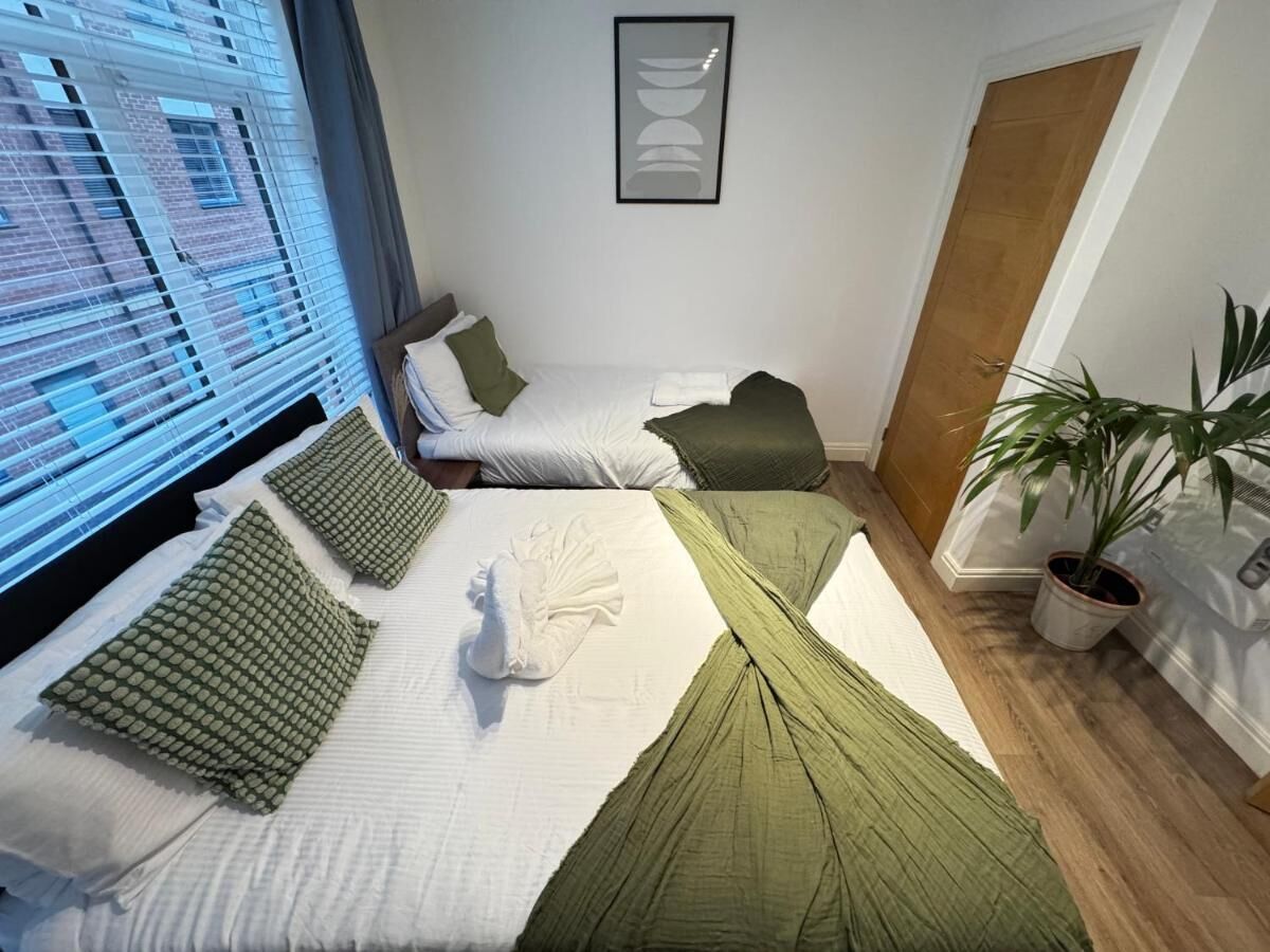 Habitación de hotel con dos camas, una planta en maceta y una obra de arte enmarcada en la pared.
