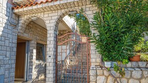 A stone building with a metal gate, a wooden door, and a potted plant. - Apartman Franjo 1 (Dramalj)