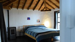 A bedroom with a wooden bed, a small heater, and a window. - Casa Madera 2 (La Vega)