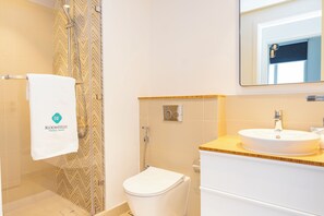 Een badkamer met douche, toilet en wastafel.