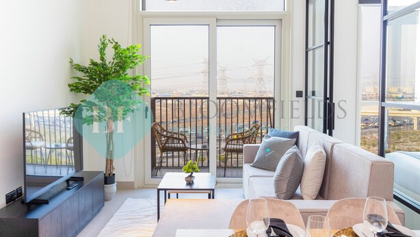 Una sala moderna con sofá, mesa de comedor y sillas, ventanas amplias con vista a la ciudad y una planta en maceta.