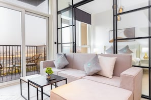 Een moderne woonkamer met een bank, een salontafel en uitzicht op de stad door grote ramen.