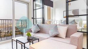 Una sala de estar moderna con un sofá, una mesa de centro y un balcón con mobiliario exterior.