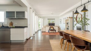 A modern kitchen with white cabinets, a wooden dining table, and a large window. - Spacious 3BR Villa with pool and views (Fuengirola)