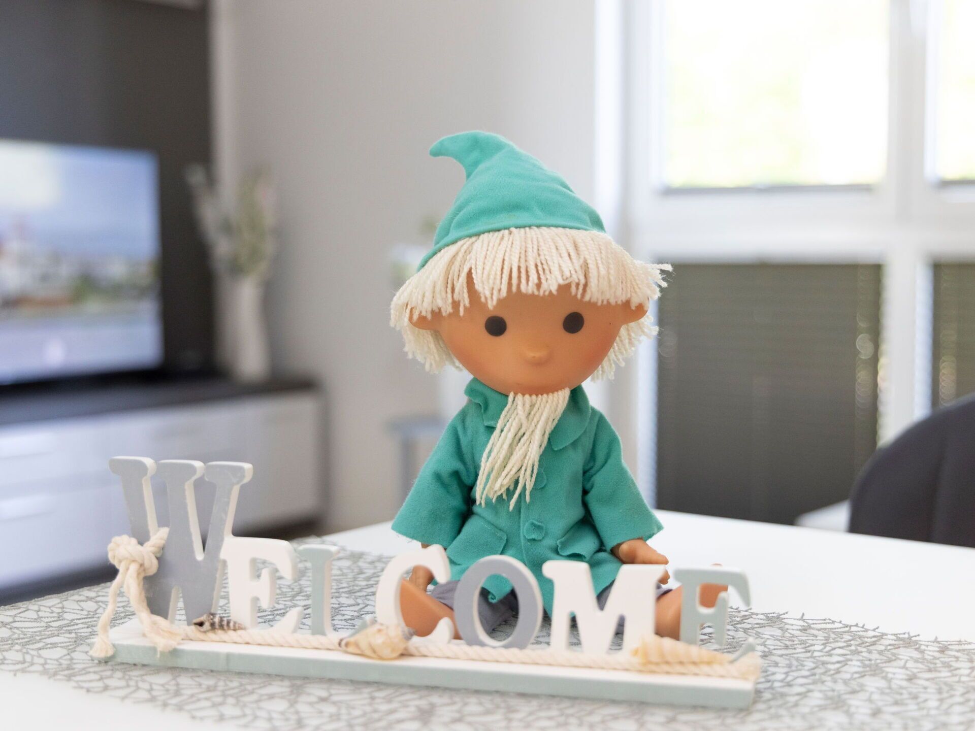 A figurine on a table with the word "WELCOME" spelled out in letters.