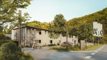 A building with a modern design, a paved road in front, and a natural landscape in the background.