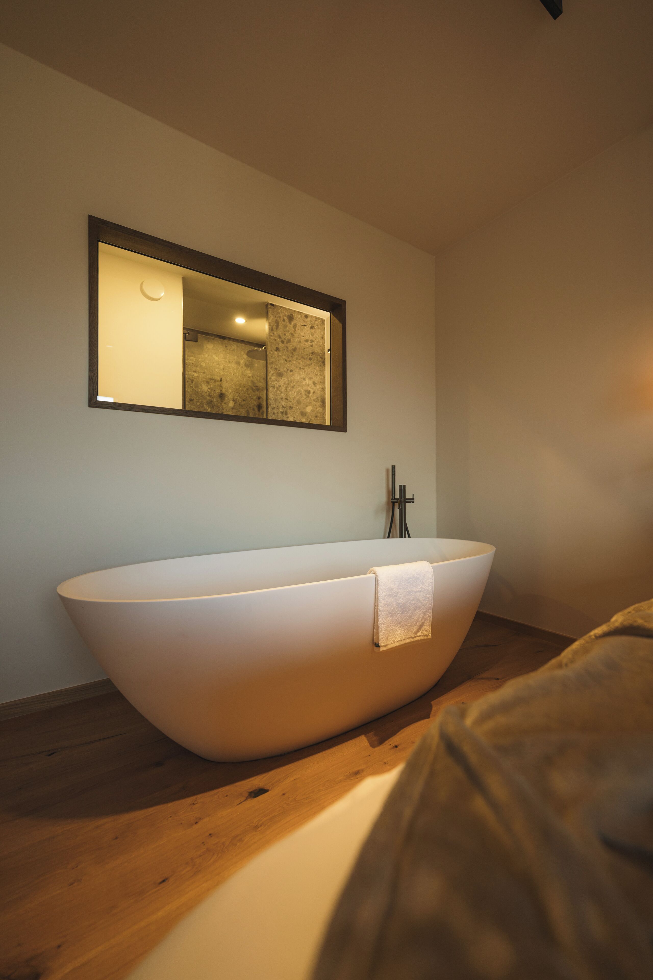 Une salle de bain moderne avec une baignoire sur pieds, un miroir au-dessus et un plancher en bois.