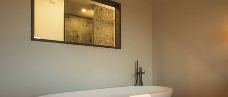 Une salle de bain moderne avec une baignoire sur pieds, un miroir au-dessus et un plancher en bois.