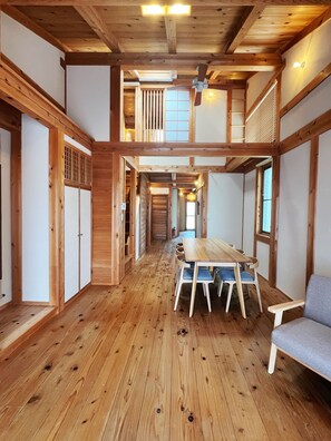 A wooden interior with a dining area, wooden floors, and a staircase leading to an upper level.