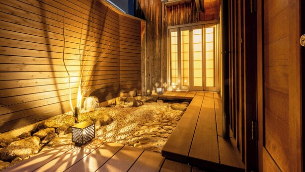 A wooden deck with a stone pathway and a lantern.