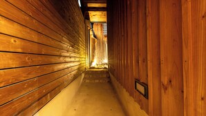 A narrow wooden hallway with a concrete floor, leading to a staircase.