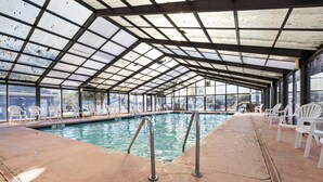 An indoor swimming pool with a glass ceiling, white chairs, and a concrete floor. - Beautiful 4B 3.5BA in Oceanside Village - Pet friendly! 2 Golf carts included! (Surfside Beach)