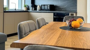 Una cocina moderna con una mesa de comedor de madera, sillas tapizadas en gris y un tazón de fruta sobre la mesa.
