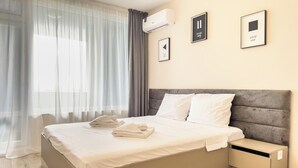 Un dormitorio moderno con una cama grande, una mesita de noche y un aire acondicionado de pared.