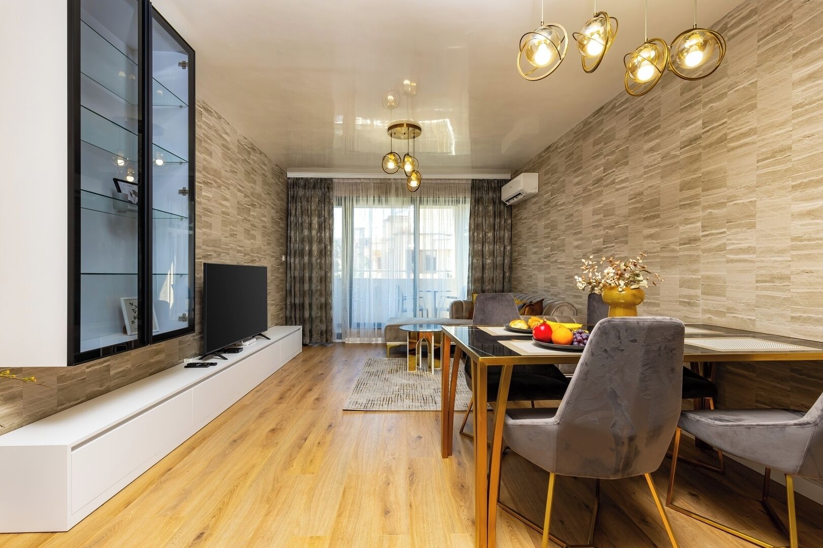 A modern living room with a flat-screen TV, dining table, and chairs.