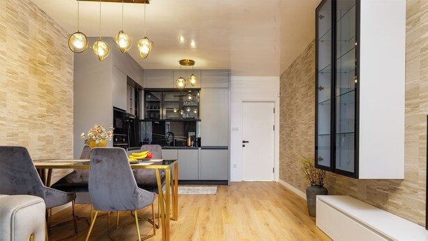 Een moderne keuken met een eethoek, houten vloeren en hangende lampen.