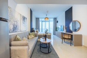A modern living room with a sofa, coffee table, and a dining area with a chair and a side table. - Bloomfields Studio in Julphar Residence-Reem (Abu Dhabi)