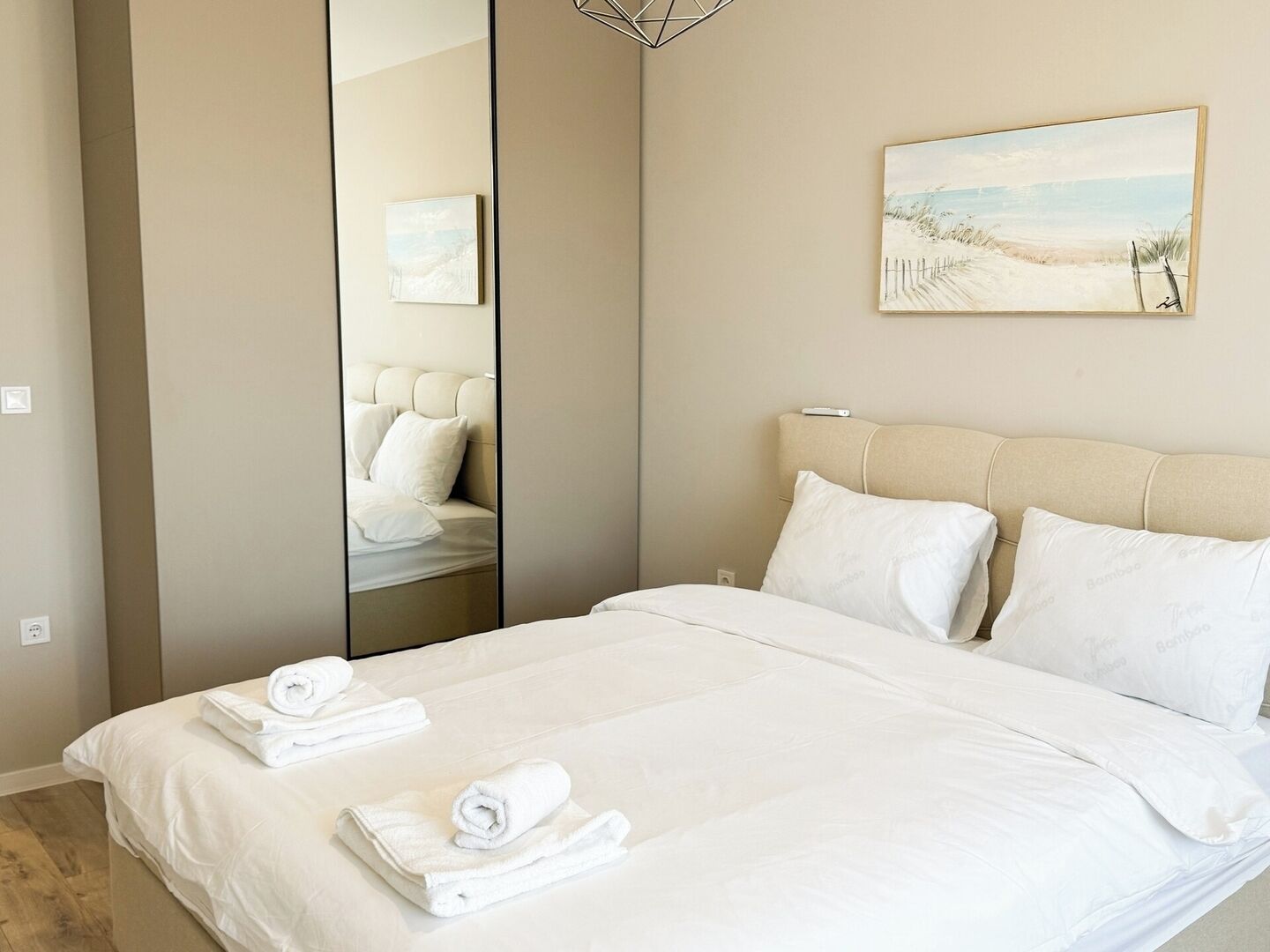 Habitación de hotel con una cama grande, un espejo y un cuadro con temática marina en la pared.