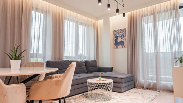 Una sala moderna con un sofá gris, una mesa redonda de centro y una mesa de comedor con sillas.