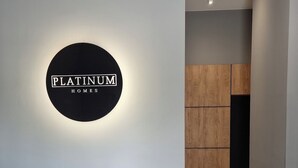 Un interior moderno con un letrero circular que dice 'PLATINUM HOMES' en una pared, un armario de madera y un piso de baldosas.