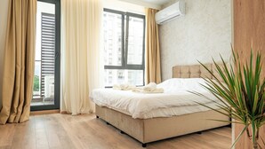 Un dormitorio con cama, cortinas, una planta en maceta y una ventana con persianas.