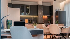 Una cocina moderna con armarios oscuros, una isla central e iluminación colgante.